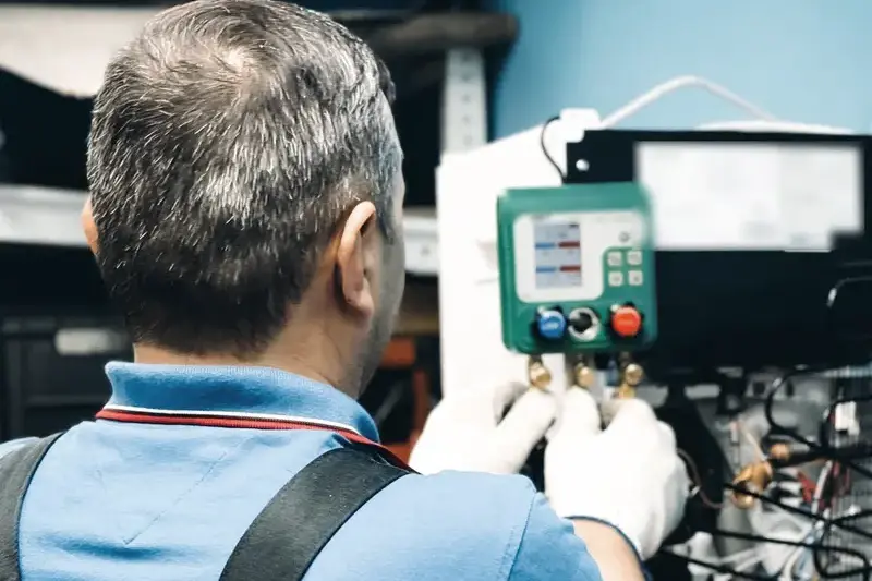 Technician in a blue work shirt connecting refrigerant gauges to a cooling unit